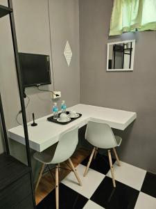 a room with a desk with two chairs and a television at AMS Hostel Butuan City in Butuan