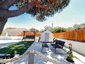 a patio with two chairs and a swing under a tree at Limnos Twin Pine in Néa Koútali