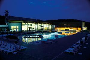 a building with a pool and chairs in front of it at Hotel Pri mostu in Dolenjske Toplice