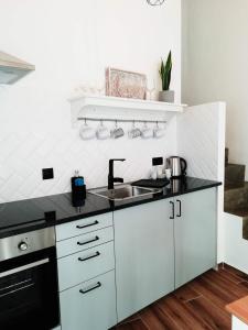 a white kitchen with a sink and a stove at Sunset Little House in Aljezur