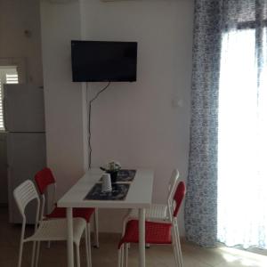 une table à manger avec des chaises et une télévision murale dans l'établissement Akrogiali Apartments, à Paralia Skotinas