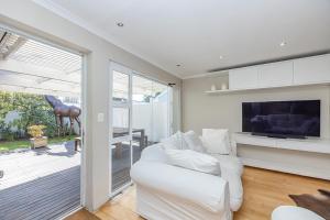 a living room with a white couch and a television at The Island Beach Villa in Cape Town