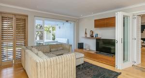 a living room with a couch and a television at The Island Beach Villa in Cape Town