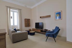 un salon avec deux chaises et une télévision dans l'établissement Brand New 2 Bed Sliema Apt, à Sliema 17 autres photos