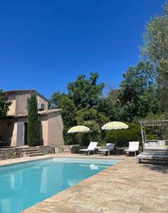 a swimming pool with two chairs and umbrellas at Maison provençale in Grimaud