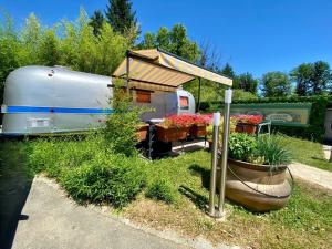 an rv with a tent and flowers in a yard at Le Clos de Tanvol - Parking privé GRATUIT- Terrasse Privée - Climatisation - Caravane Airstream in Viriat
