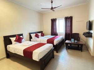 a hotel room with two beds and a tv at Harish Beach Resort in Rāmeswaram
