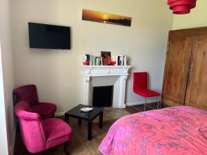 PluguffanにあるStudio à la Petite Boissière proximité des plages et de la gare SNCFのベッドルーム1室(ベッド1台、椅子2脚、暖炉付)