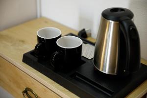 a black and silver coffee pot and two cups on a counter at Rest & View Guesthouse in Gjirokastër