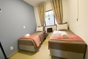 two beds in a room with a window at Linda Casa com 2quartos para 5 pessoas in Foz do Iguaçu