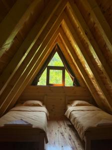 two beds in a log cabin with a window at Guesthouse Stanisic in Dobrilovina