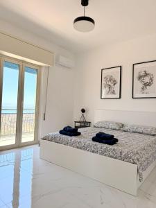 een witte slaapkamer met een bed en een groot raam bij La casa delle parole 2 in Agrigento