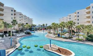 a pool at the resort with palm trees and buildings at Gulf-Front Waterscape B401 Sundrenched in Fort Walton Beach