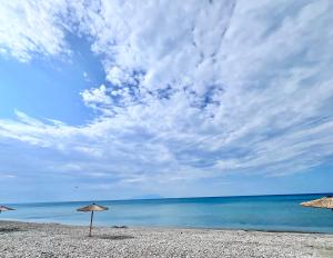 two straw umbrellas on a beach with the ocean at The Beach house in Platanitis