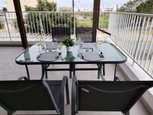 a glass table and two chairs on a balcony at Apartment Sun Kapparis in Paralimni