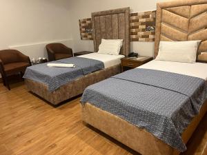 a hotel room with two beds and a chair at Amada Family Guest House in Karachi