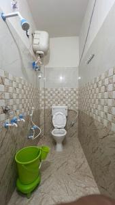 a bathroom with a toilet and a green bucket at Kanak Bihari Yatri Niwas, 100 Meter Ram Ki Paidi, Saryu River in Ayodhya
