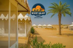 斋沙默尔desert Galaxy Camp Jaisalmer的沙漠山谷营地的标志，上面有一棵棕榈树和一些帐篷