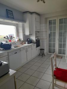 a kitchen with white cabinets and a sink and a window at Maison familiale, front mer in Lanildut