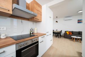 a kitchen with a stove top oven next to a living room at ColorsVibe Apartment in Trogir