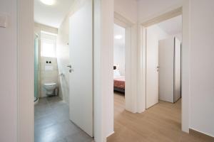 a white bathroom with a toilet and a bed at ColorsVibe Apartment in Trogir +20 photos