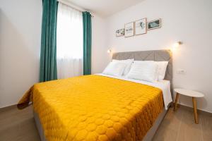 a bedroom with a large bed with a yellow blanket at ColorsVibe Apartment in Trogir