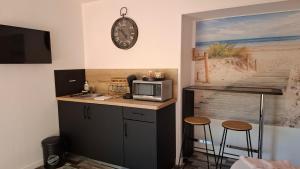 a kitchen with a counter with a microwave and a clock at chambre d'hotes studio des tourterelles in Champniers