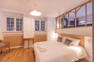 1 dormitorio con 1 cama blanca grande y ventanas en La p'tite barque des remparts Mer, en Saint-Malo