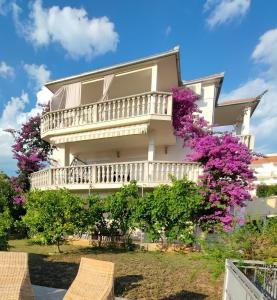 a large house with a balcony and purple flowers at Apartmani Jureta in Okrug Gornji