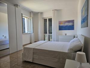 a white bedroom with a bed and two windows at La CASA degli IPPOCASTANI in Colonnella