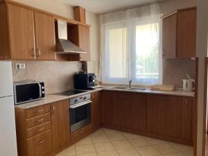 a kitchen with wooden cabinets and a sink and a microwave at Apartman N in Pusztavacs