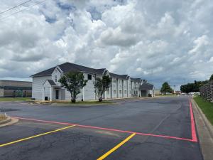 een lege parkeerplaats met een groot wit gebouw bij Americas Best Value Inn and Suites Ada in Ada