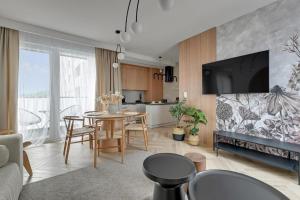a living room with a table and a kitchen at Family & Business Sauna Apartments Baltic Horizon No 1 PREMIUM SPA - 3 Bedroom with Private Sauna, Jacuzzi, Rooftop Gym & Panoramic Terrace, Balcony, Underground Garage in Gdańsk
