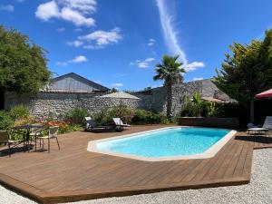 a swimming pool on a wooden deck next to a house at Le clos des grandes rivières in Sainte-Soulle