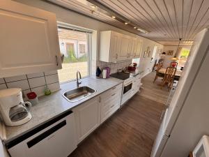 a kitchen with white cabinets and a sink at Fynshav in Augustenborg