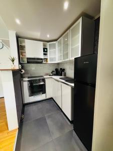 a kitchen with white cabinets and a black refrigerator at Kleine Auszeit in Bad Kreuznach