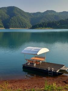 a dock with an umbrella and benches on the water at Vikendica Jagoš in Mitrovac