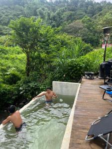 two men are in the water in a pool at Tiny House in Dahilayan in Manolo Fortich