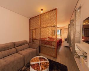 a living room with a couch and a bedroom at Villa Ida Acomodações, Suítes Aconchegantes e Charmosas no Centro in Serra Negra