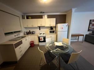 a kitchen with a glass table and white appliances at Makkadesh Homes in Bunbury