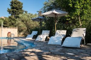 a group of chairs and an umbrella next to a pool at Antheia Houses in Vamos