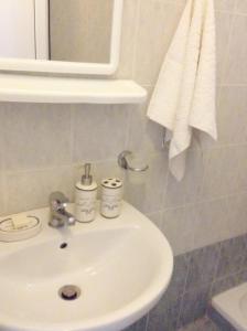 Akrogiali Apartments في باراليا سكوتنيس: حمام مع حوض أبيض ومرآة