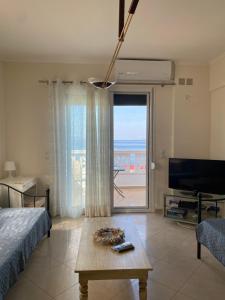 ein Wohnzimmer mit einem Bett, einem Tisch und einem Fernseher in der Unterkunft Orsalia's Apartment in Neapolis