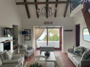 un soggiorno con divano, sedie e lampadario pendente di Little Breede Cottage a Witsand