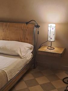 a lamp sitting on a night stand next to a bed at Il giardino di fronte in Saluzzo