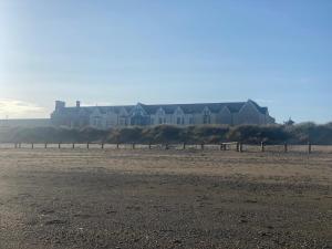 a row of houses on the beach with a house in the background at Explorer Room Ensuite Mountain View 3rd floor in Pwllheli