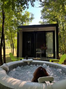 a woman laying in a hot tub in a backyard at Frutak Resort-TINY HOMES in Danilovgrad
