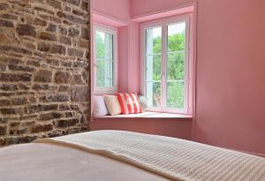 a bedroom with pink walls and a brick wall at La Maison de Cécile in Cahan