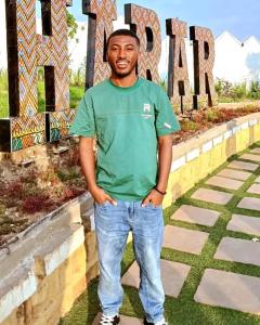 Un hombre con una camisa verde de pie frente a un cartel en Djibouti hotel room, en Dire Daua