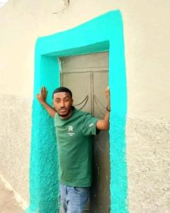 Un hombre está parado en una puerta azul. en Djibouti hotel room, en Dire Daua